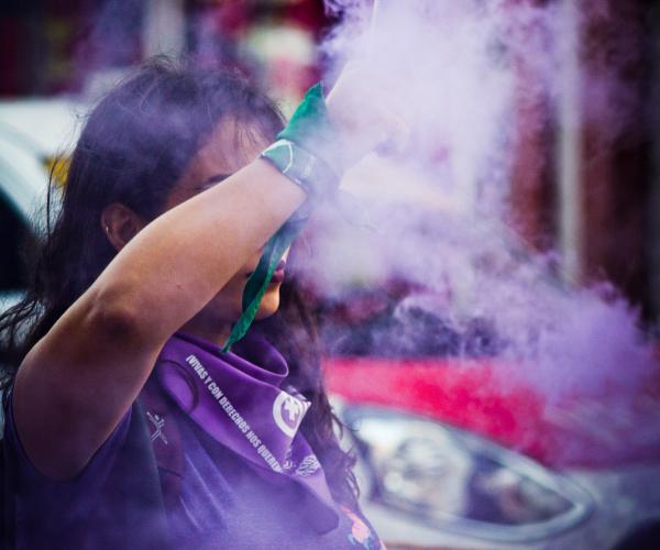 purple smoke around woman at protest